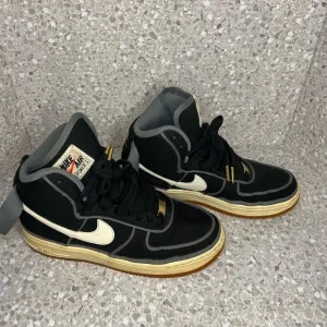 Nike Air Force 1 in Black Canvas. Gold Accents on laces.